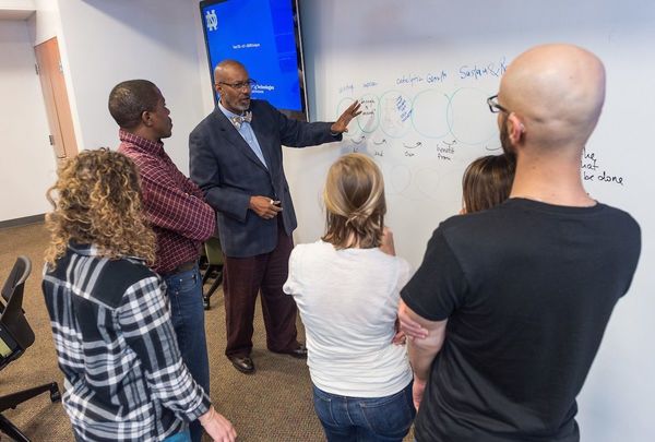 David Hooker, associate professor of the practice of conflict transformation and peacebuilding, teaching at a whiteboard with students looking on